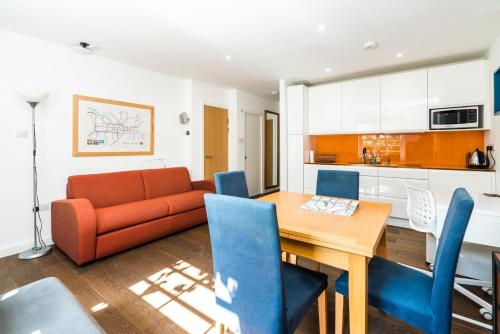 a living room with a orange couch and a wooden table at Charming 2 Bedroom Apartment in Kentish Town in London