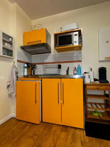 - une cuisine avec des armoires orange et un four micro-ondes dans l'établissement Chez Cyril et Angelique, à Cauterets