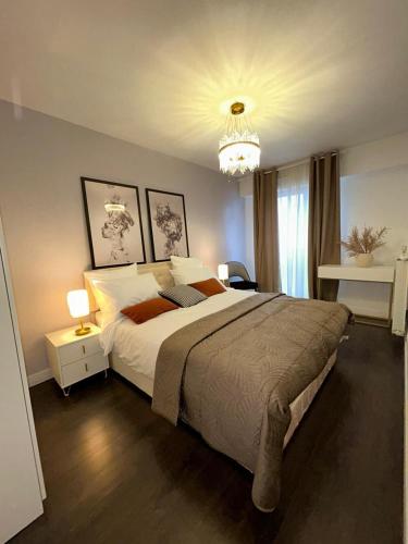 une chambre avec un grand lit et un lustre dans l'établissement Le confort et l'élégance à deux pas de Paris, à Cachan