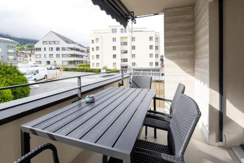 a wooden table and chairs on a balcony with a view at STAYY Rigi Suites - Self-check-in Premium Apartments - 20min to Lucern - 7min Walk to Lake - Public Transport - Washer Dryer in Küssnacht