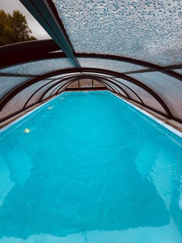 a swimming pool with a ceiling and blue water at Osada Modrzewiowe Wzgórze Bieszczady in Ustrzyki Dolne