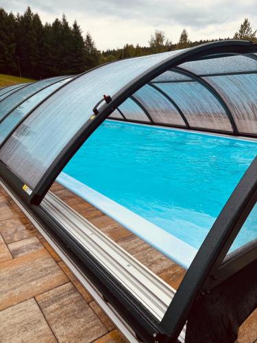 a view of a pool from under a metal roof at Osada Modrzewiowe Wzgórze Bieszczady in Ustrzyki Dolne