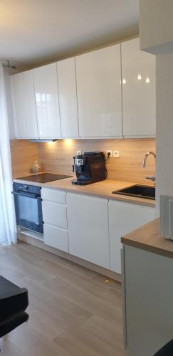 une cuisine avec des armoires blanches et un évier dans l'établissement Arènes chambre privée appt a partager, à La Celle-sous-Gouzon