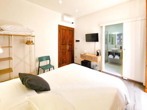 a white bedroom with a bed and a chair at Il Caracolo Rooms in La Maddalena