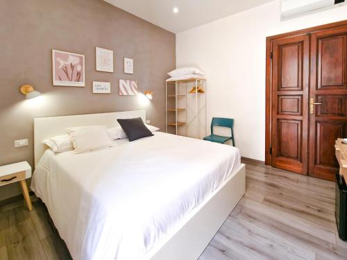 a bedroom with a large white bed and a wooden floor at Il Caracolo Rooms in La Maddalena