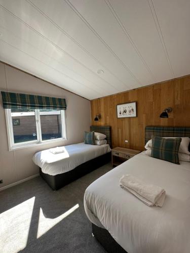 a hotel room with two beds and a window at Sandy Lane 18 - Lodge with Hot Tub in Allerthorpe