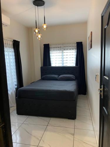 a bedroom with a bed with black sheets and windows at Boa vista appartementen in Paramaribo