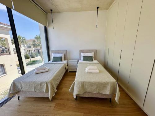 two beds in a room with a large window at Elysian Blue villa 4 in Paphos City