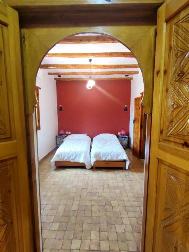 a bedroom with two beds and a red wall at Villa Riad Ahlam in Sidi Kaouki