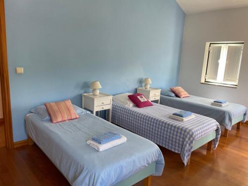 three beds in a room with blue walls at Casa dos castanheiros in Ponte de Lima