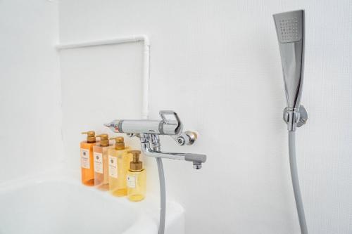 大阪市にあるSUIMEI Ebisuの黄色いオイルボトルが置かれたシャワー付きのバスルーム
