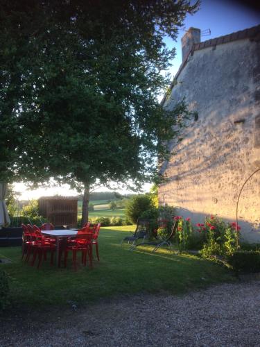 a table and chairs in a yard next to a wall at Gite L'ENTRE DEUX in Doumen