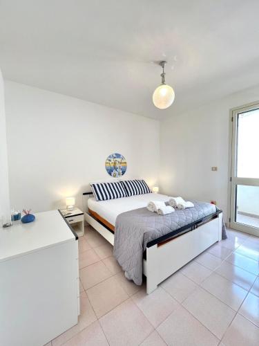 een witte slaapkamer met een bed en een raam bij Holiday salento in Leuca