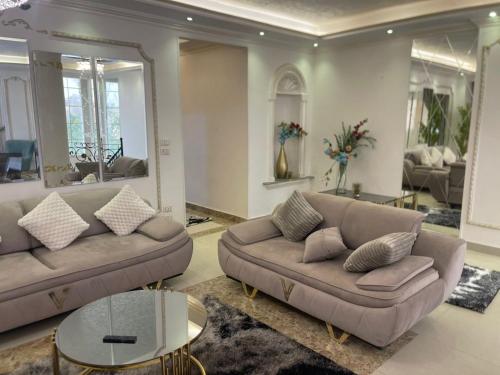 a living room with two couches and a table at modern villa with coverable pool sheik zayed in Sheikh Zayed
