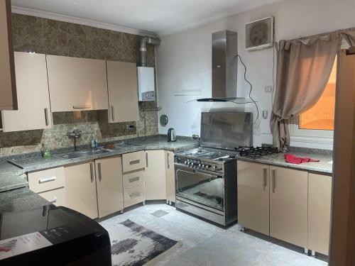 a kitchen with white cabinets and a stove top oven at modern villa with coverable pool sheik zayed in Sheikh Zayed