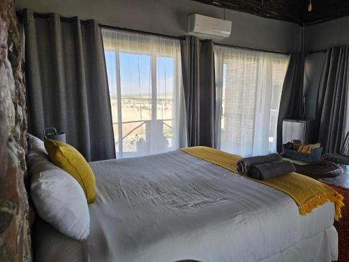 a bedroom with a large bed with a large window at Carlo's Mountain Lodge in Usakos