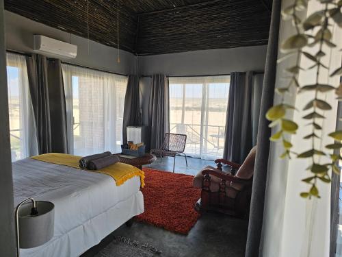 a bedroom with a bed and a chair and windows at Carlo's Mountain Lodge in Usakos