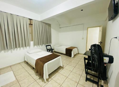 a hotel room with two beds and a desk at Hotel Gran Solar Br in Contagem