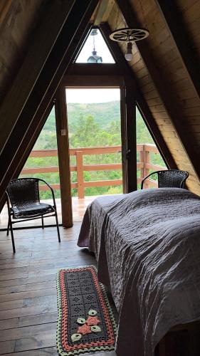 MunhozにあるPousada Pedra da Mata chalés na montanhaのベッドと大きな窓のある寝室