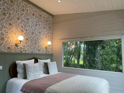 ein Schlafzimmer mit großem Bett und Fenster in der Unterkunft Le cottage du Manoir 1900 in La Ferté-Gaucher