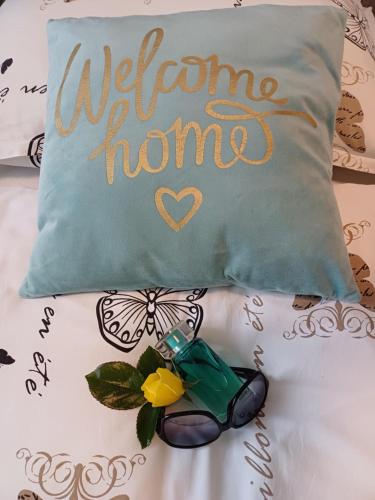 a welcome home pillow with a butterfly on a bed at Unicum Vendégház in Abádszalók