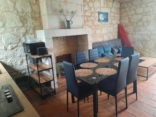 a dining room with a table and chairs and a fireplace at Gîte aux Pissenlits in Brain-sur-Allonnes