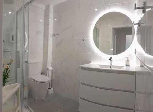 a white bathroom with a sink and a mirror at Vistas Sobre O Rio Tejo in Lisbon
