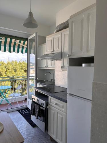 Il comprend une cuisine avec des placards blancs et offre une vue sur une terrasse. dans l'établissement Dolce Vita, à Nice