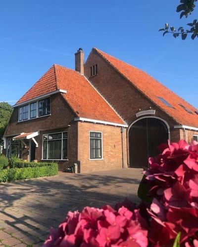 a large brick building with a red roof at Rustig logeerverblijf aan de rand van de stad in Lekkum