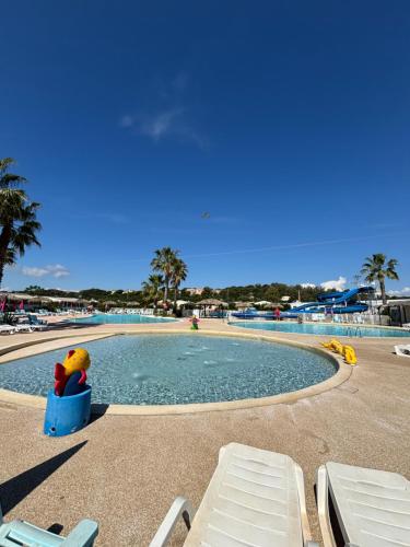 un canard en peluche est assis sur une chaise à côté d'une piscine dans l'établissement Mobil home camping 4 étoiles, à Fréjus