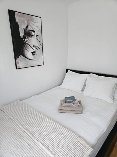 a white bed with a picture on the wall at Apartman Mila in Zagreb