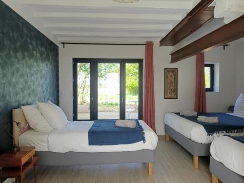 a bedroom with two beds and a window at Les Chambres d'Emma in Le Liège