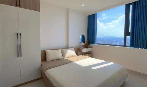 a bedroom with a large bed and a large window at Joie Apartment Hue in Thôn Văn Dương