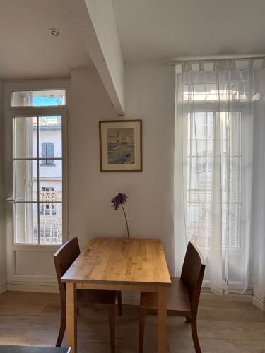 - une salle à manger avec une table en bois et 2 fenêtres dans l'établissement Studio plages du Mourillon, à Toulon