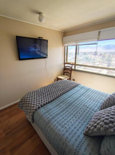a bedroom with a bed and a tv on the wall at Excelente Depto-2hab-2bañós in Calama