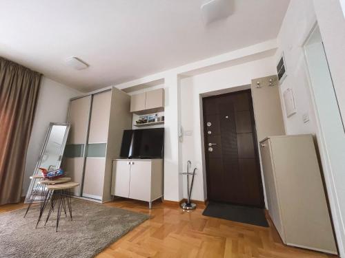 a living room with a black door and a television at Apartmani TEO in Prokuplje