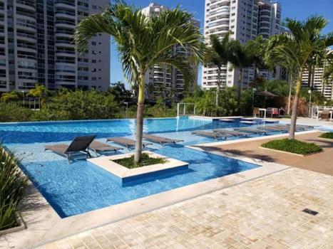 a swimming pool with a palm tree in a city at Ilha Pura BARRA apart in Rio de Janeiro