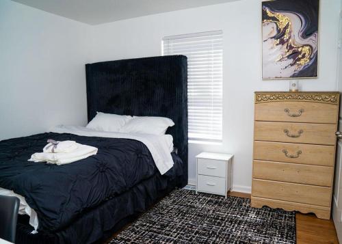 a bedroom with a bed with a black headboard and a dresser at Anike's Place in Newark