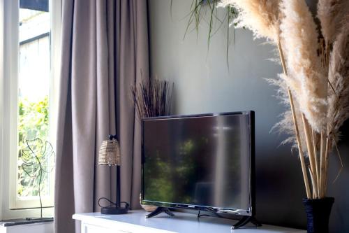 a flat screen tv sitting on a table next to a window at Vorstelijk verblijf Alkmaar in Alkmaar
