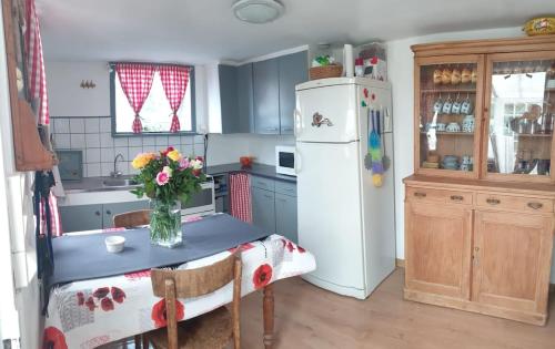 a kitchen with a table and a refrigerator at Pink Granite Coast Cottage between forest and sea in Trélévern