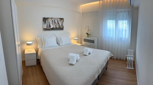 a white bedroom with a large bed with towels on it at Vistas Sobre O Rio Tejo in Lisbon