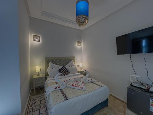 a bedroom with a bed and a flat screen tv at Riad Tonaroz Gold in Marrakech