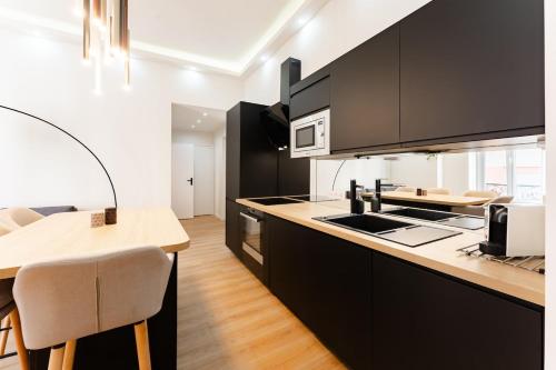 une cuisine avec des armoires noires et un comptoir en bois dans l'établissement Ambiance cosy a la Niçoise, à Nice