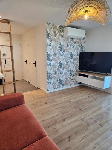 un salon avec un canapé et une télévision à écran plat dans l'établissement Bluemaya à La Grande Motte, à La Grande Motte