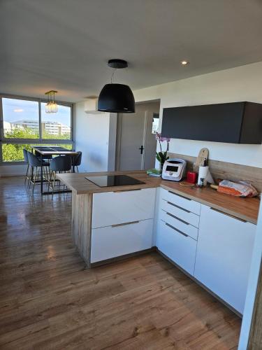 une cuisine avec des placards blancs et une salle à manger avec une table dans l'établissement Bluemaya à La Grande Motte, à La Grande Motte