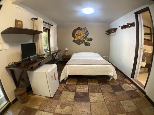 a bedroom with a bed and a desk and a computer at Lendas do Capão Pousada in Vale do Capao