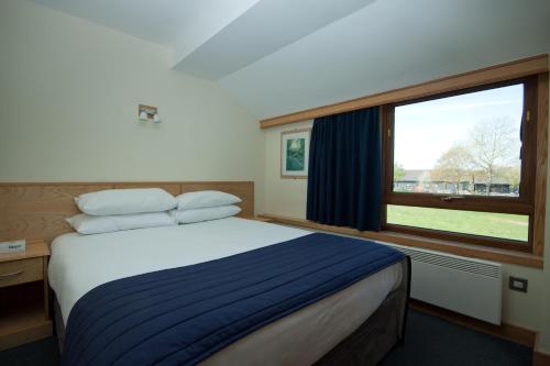 a bedroom with a bed and a large window at Weald of Kent Golf Course and Hotel in Maidstone