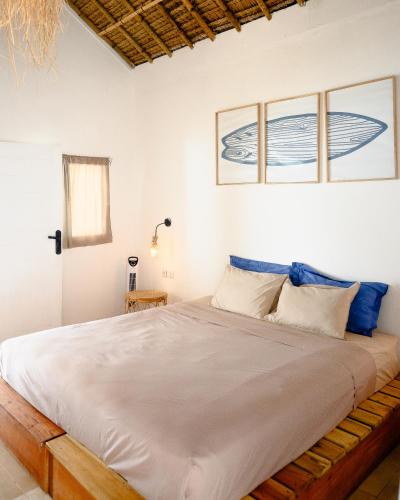 a bedroom with a large white bed with blue pillows at Surf Shack Grupuk in Bumbang