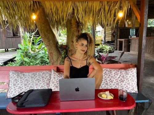 a woman sitting at a table with a laptop at TerrAmor Ecoliving in Alter do Chao