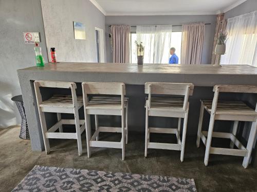 a counter with three stools and a bar with a counter top at Carlo's Mountain Lodge in Usakos